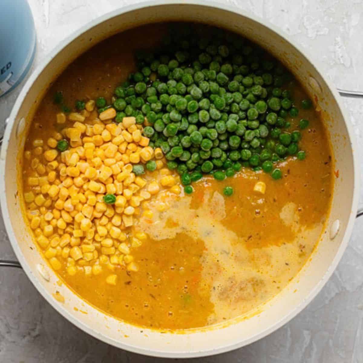 Frozen corn and peas added to creamy soup base.