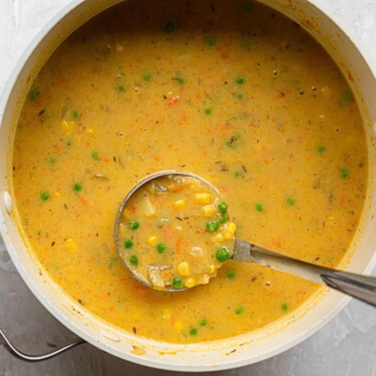 Ladle lifting up soup to show consistency.