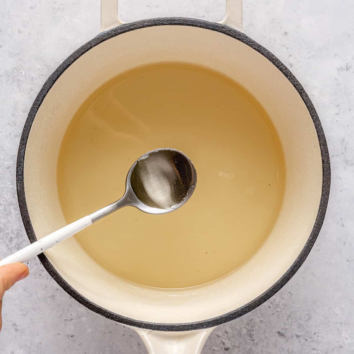 Spoon lifting up simple syrup from pot.