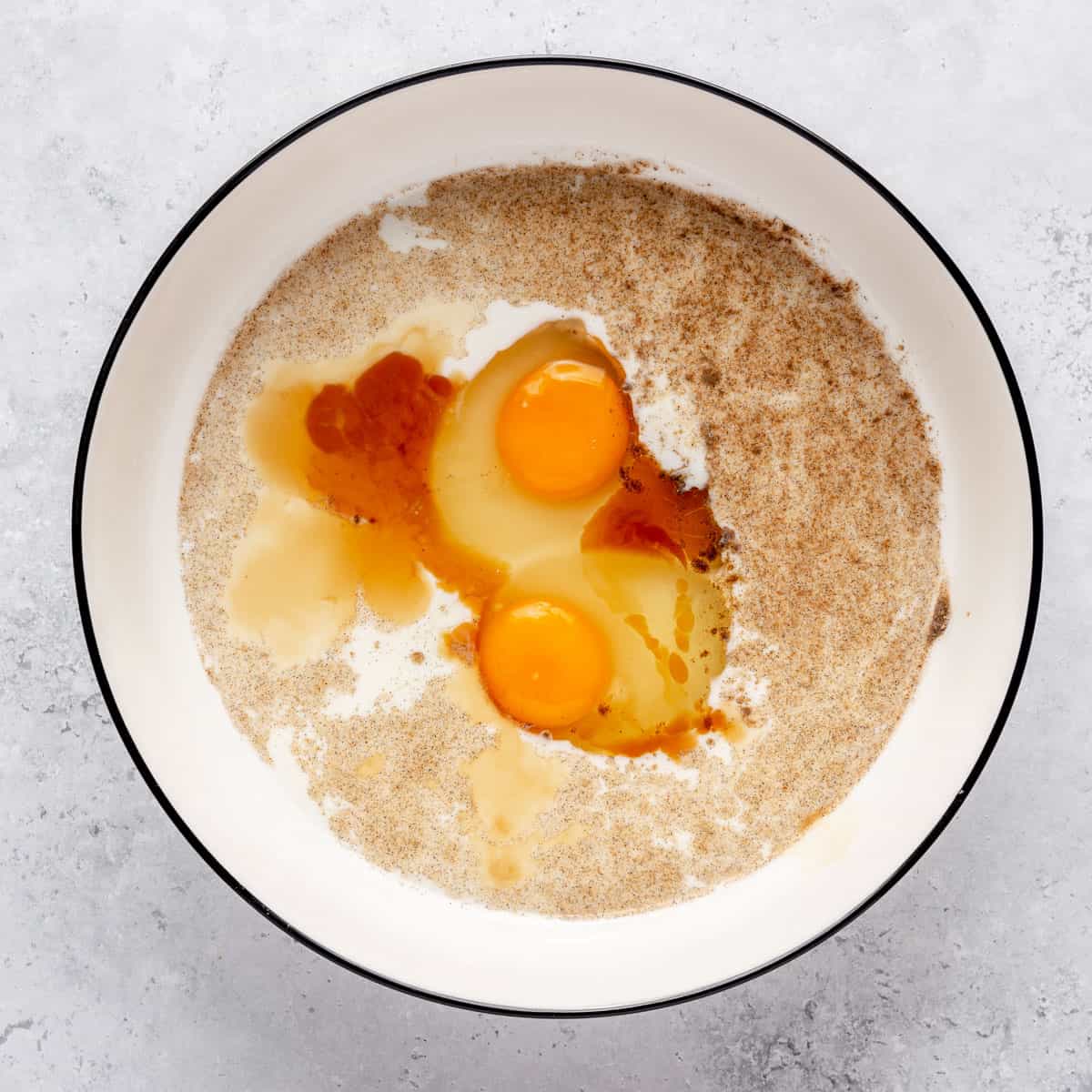 Milk, eggs, sugar, cardamom and vanilla in a bowl before mixing.