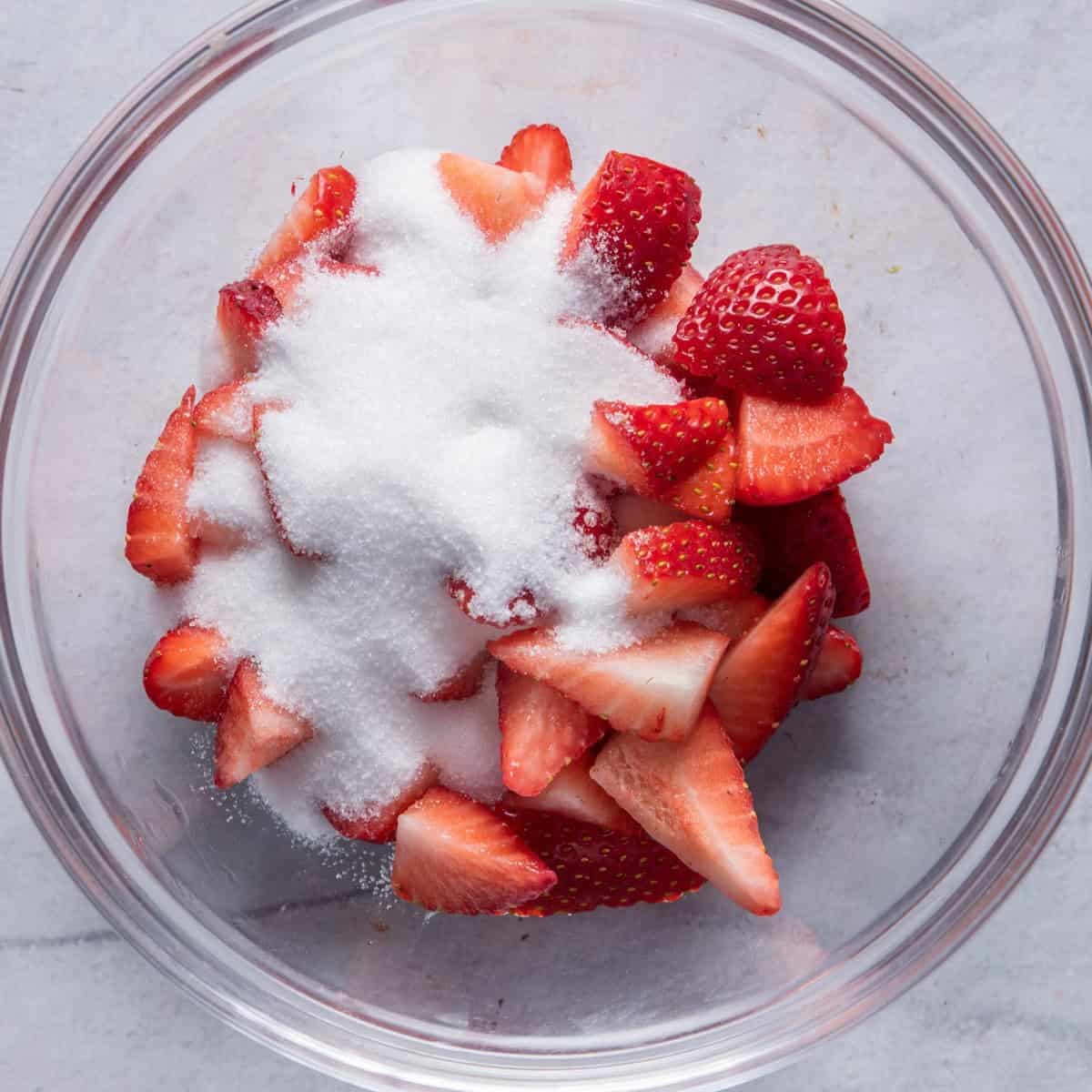 Chopped strawberries in a bowl with sugar.