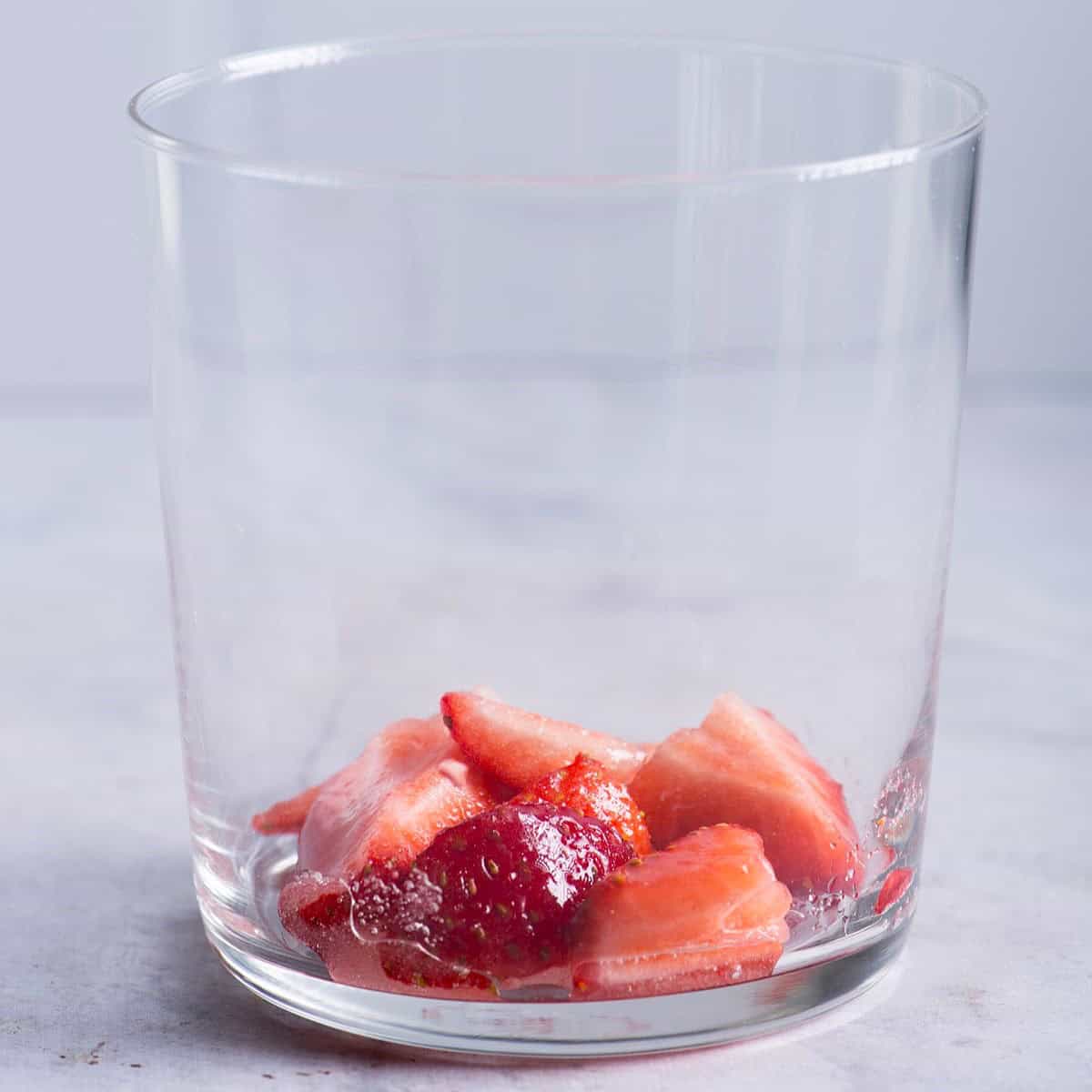 Chopped strawberries added to a small glass.