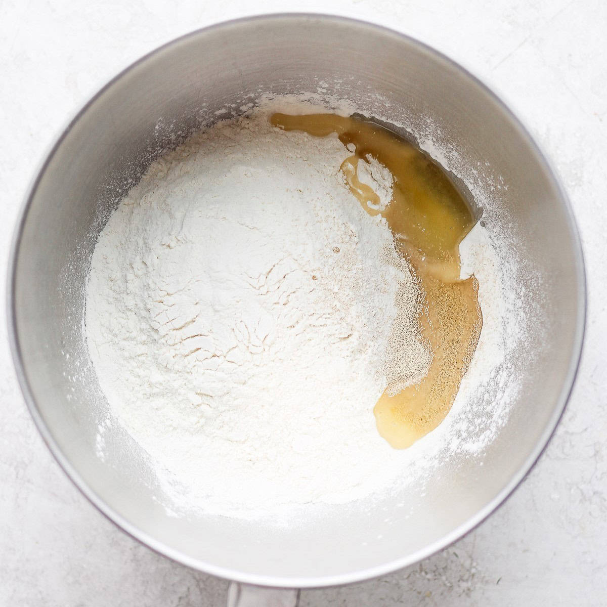 Flour, salt, sugar, oil, and yeast in the bowl of a stand mixer.