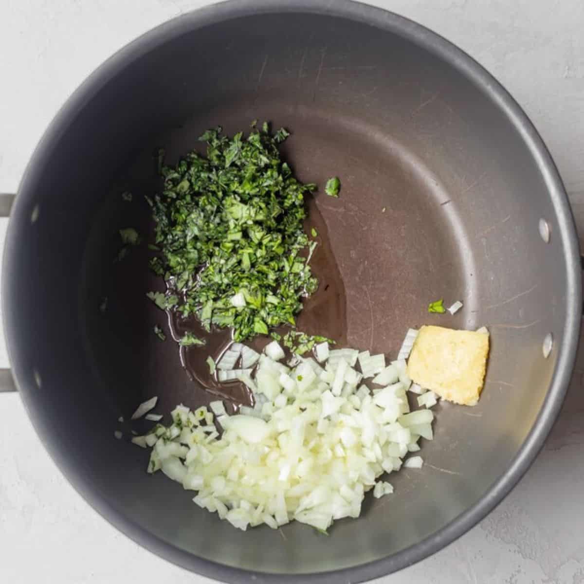 Diced onion, garlic and herbs in a pot.