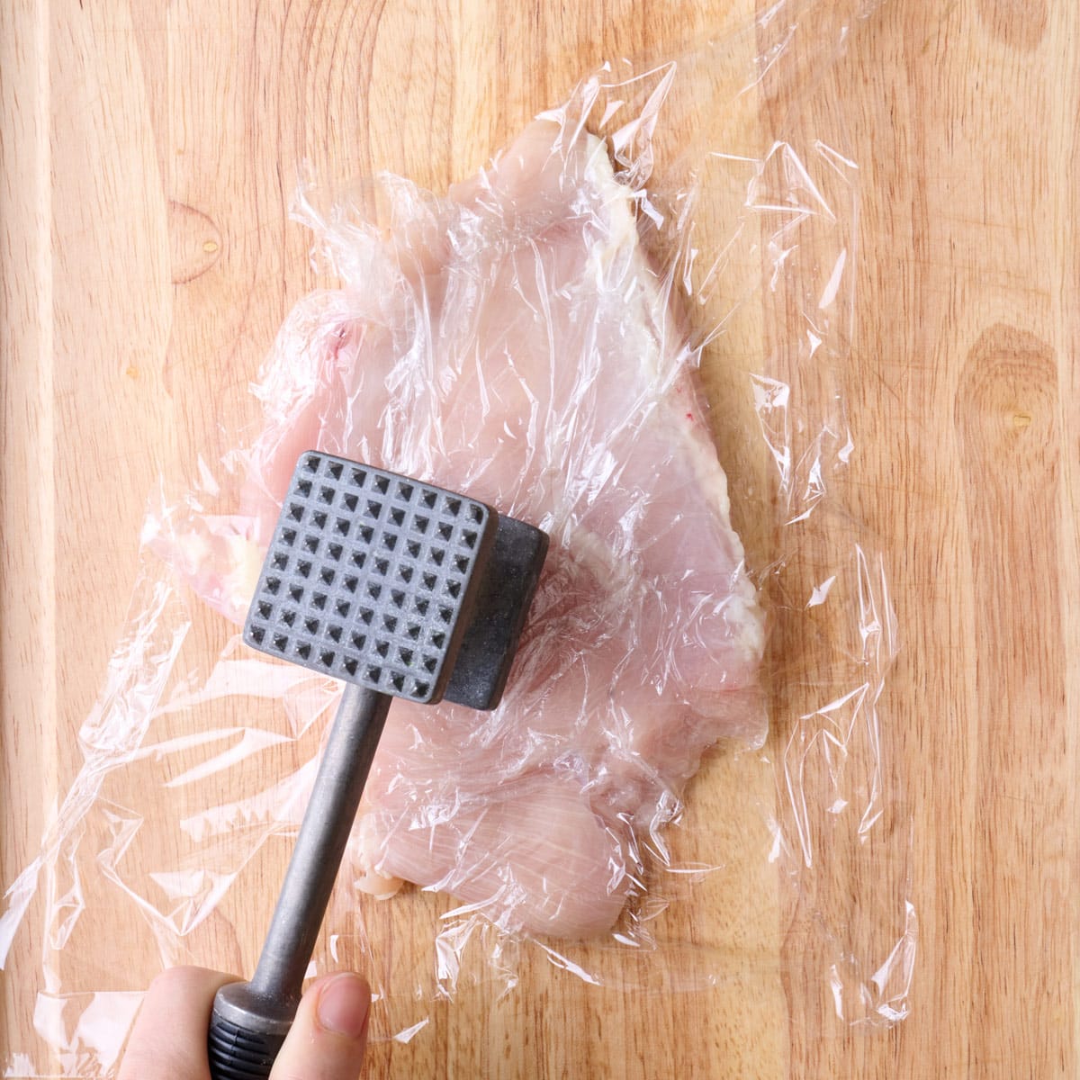 Pound a chicken breast on cutting board.