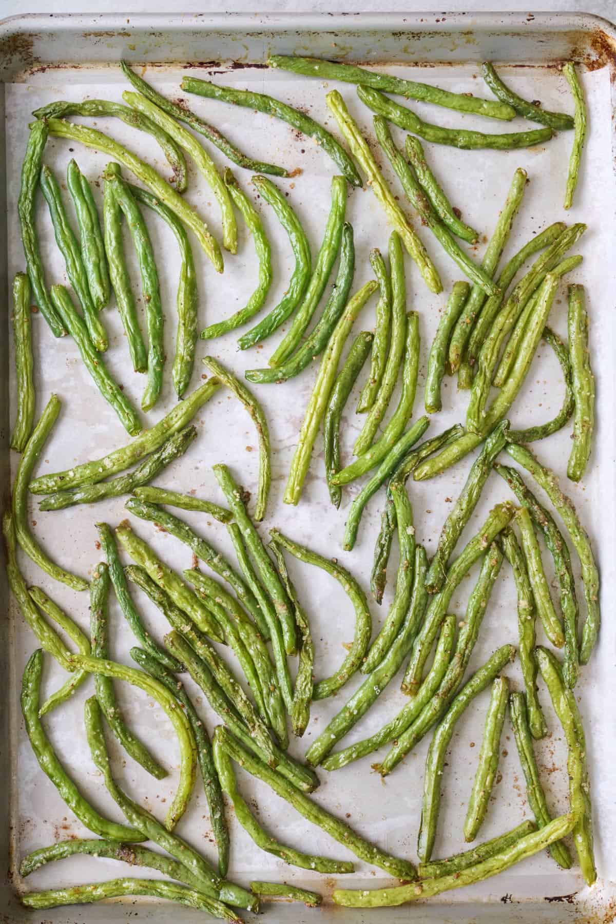 Seasoned green beans on a sheet pan after roasting.