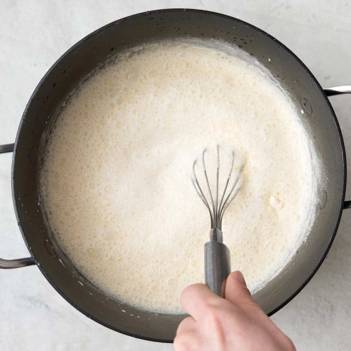 Whisking together milk, semolina, and sugar in small pot.