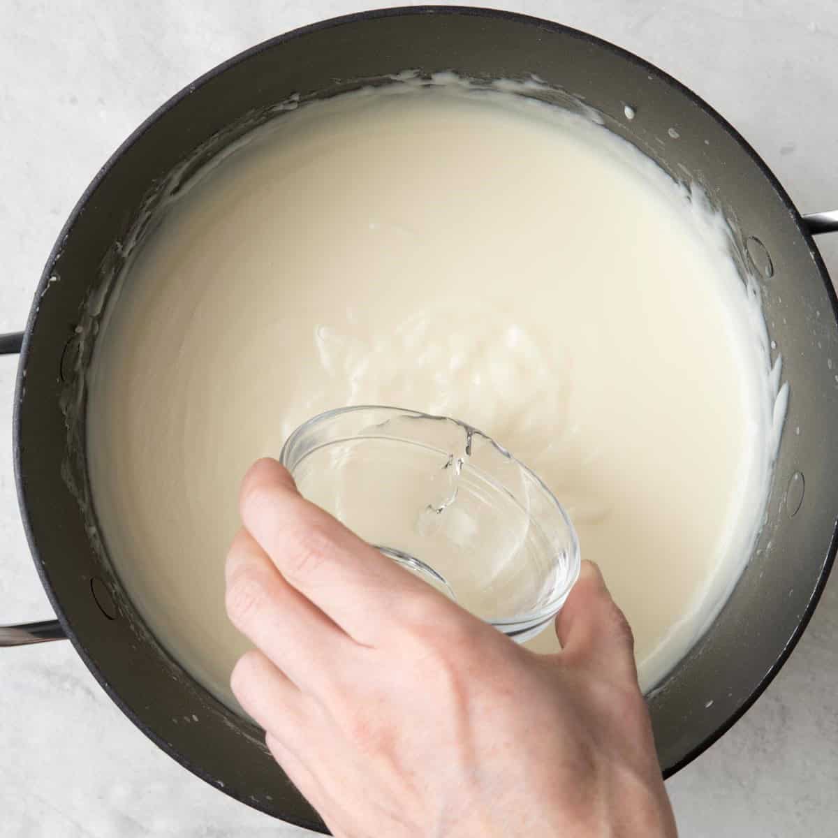 Orange blossom water being drizzled after mixture is fully dissolved and creamy.