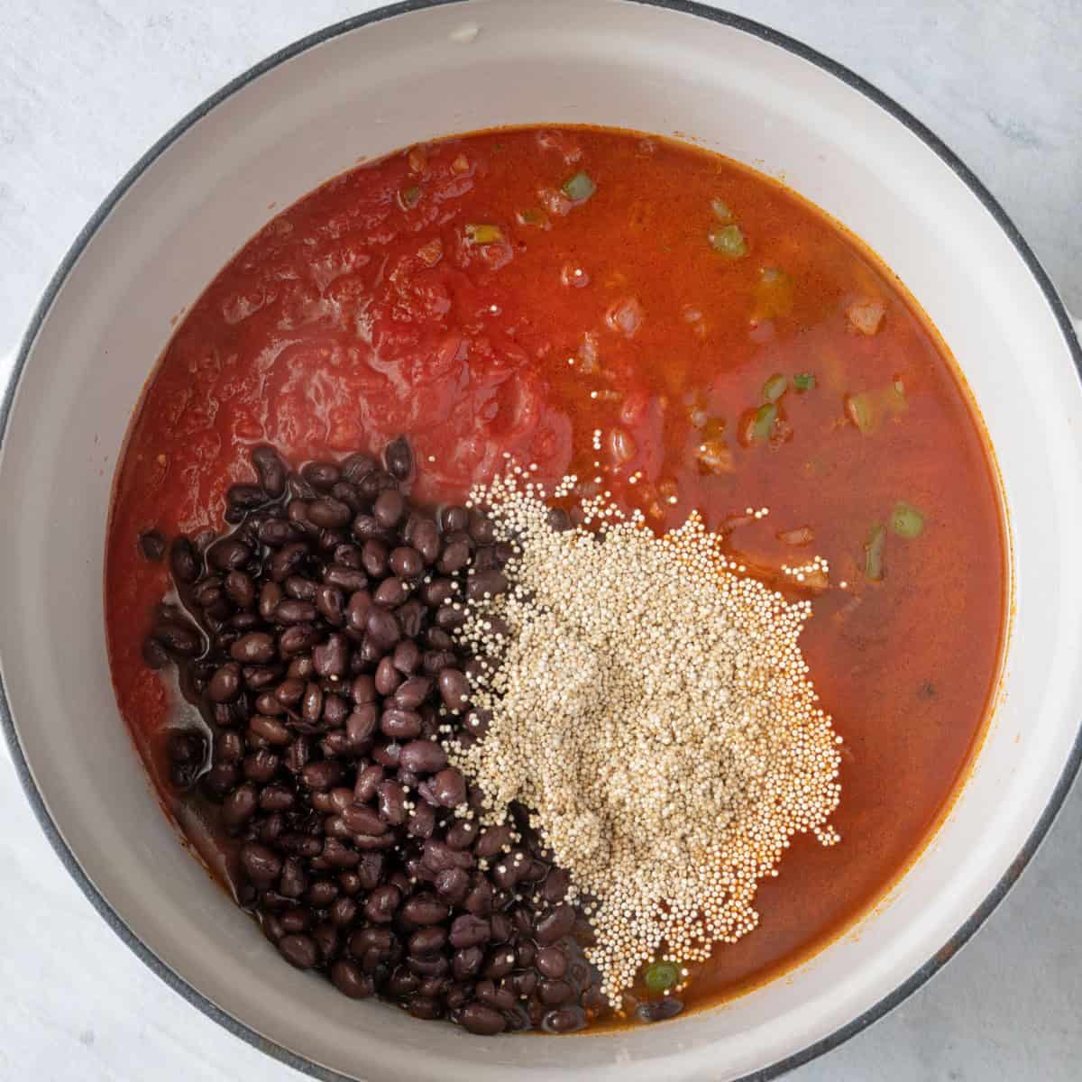 Tomatoes, black beans, quinoa, and water added to pot.