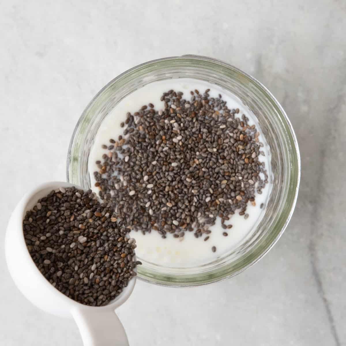 Adding chia seeds to milk in a jar.