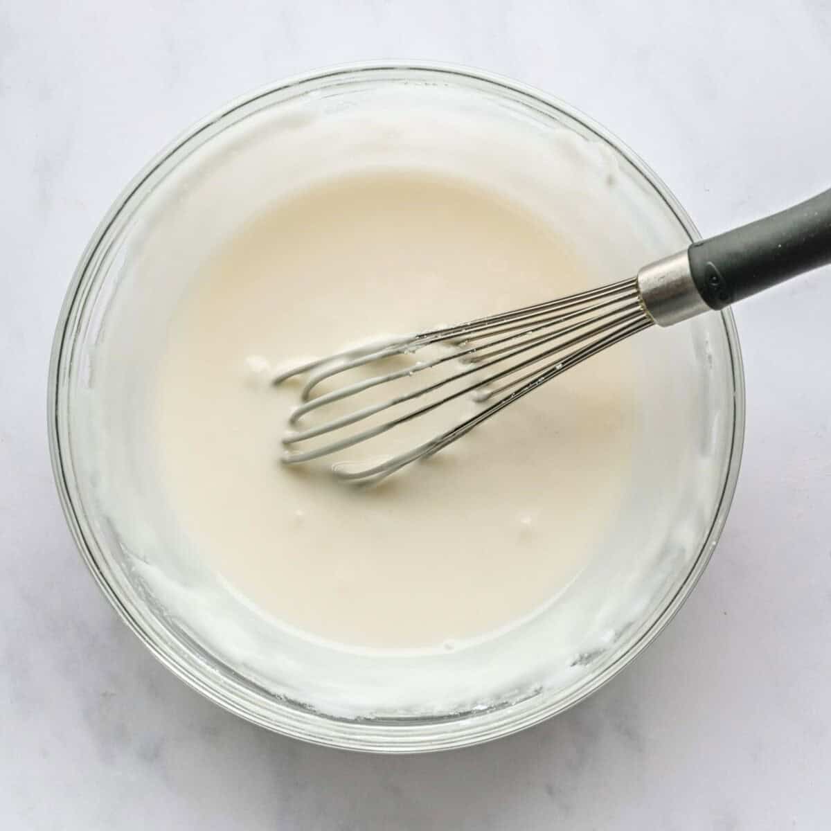 Peppermint glaze in a bowl with whisk.