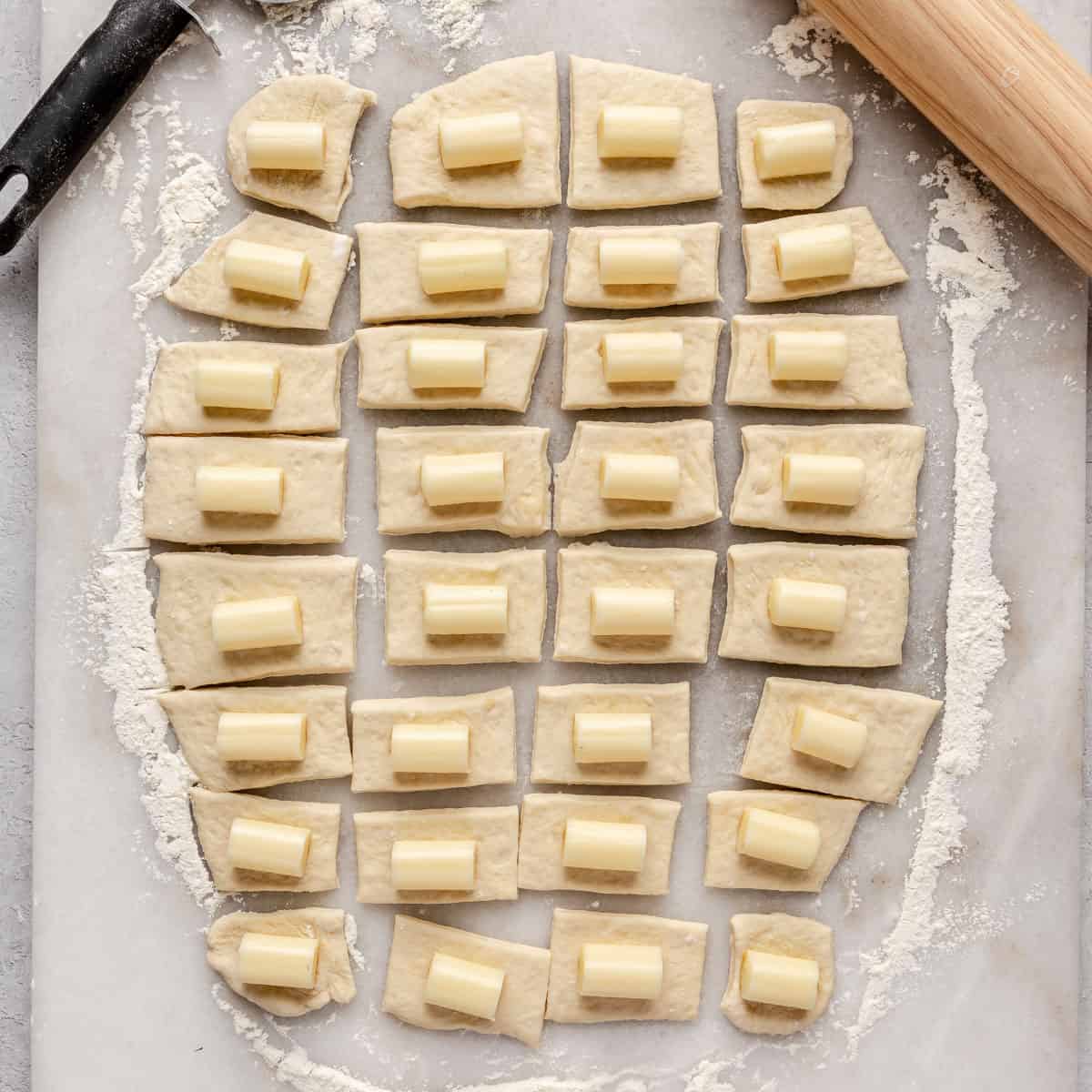 Dough pieces flattened into a square or rectangle with a piece of cheese added.