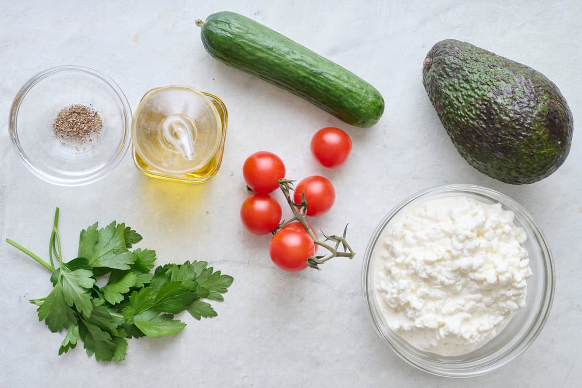 Ingredients for the savory version of recipe: pepper, oil, parsley, tomatoes, cucumber, avocado, and cottage cheese