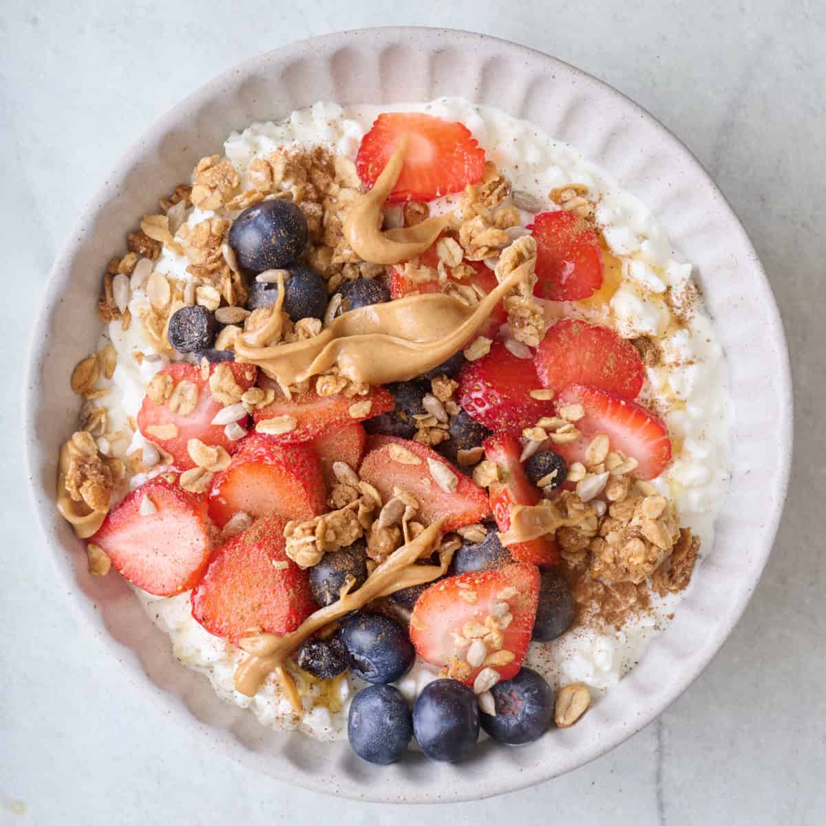 Cottage cheese bowl with fruit, nut butter, honey, and granola.