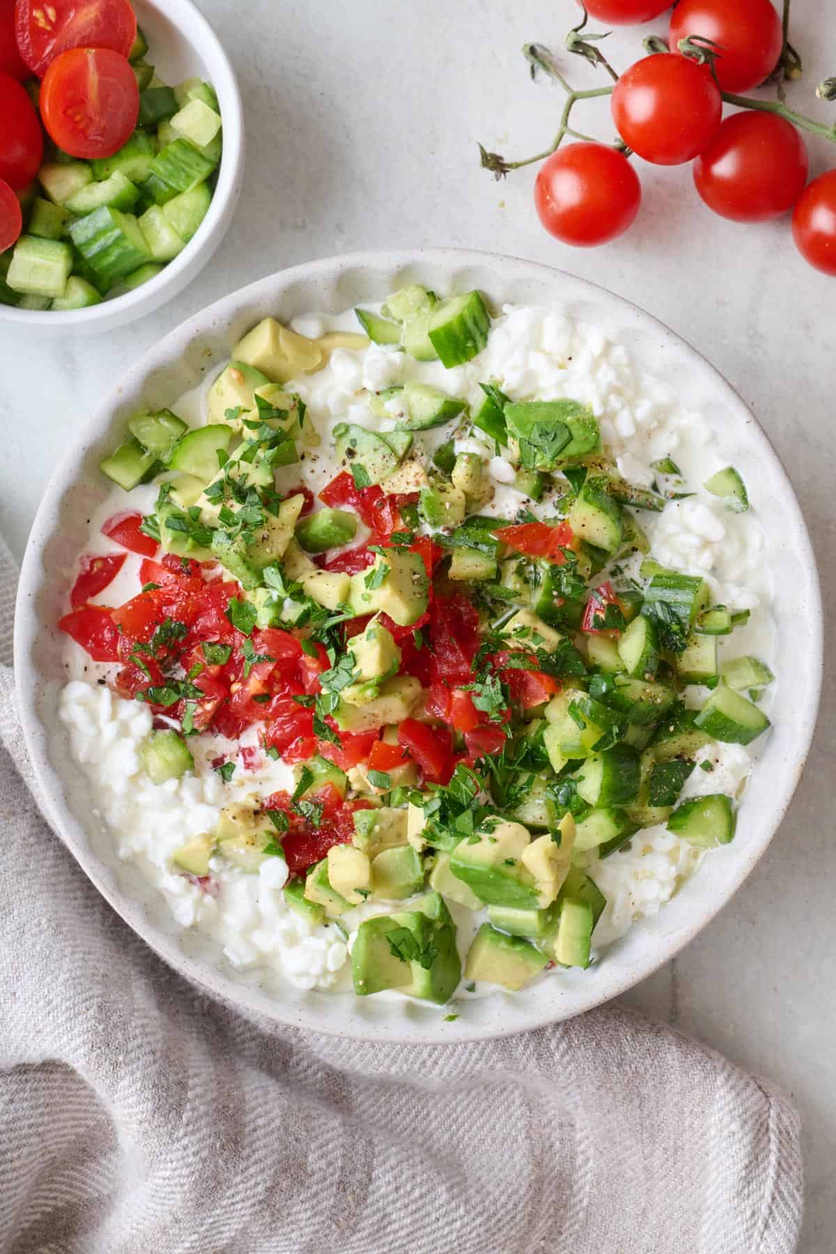 Savory cottage cheese bowl with chopped vegetables, fresh herbs, salt and pepper.