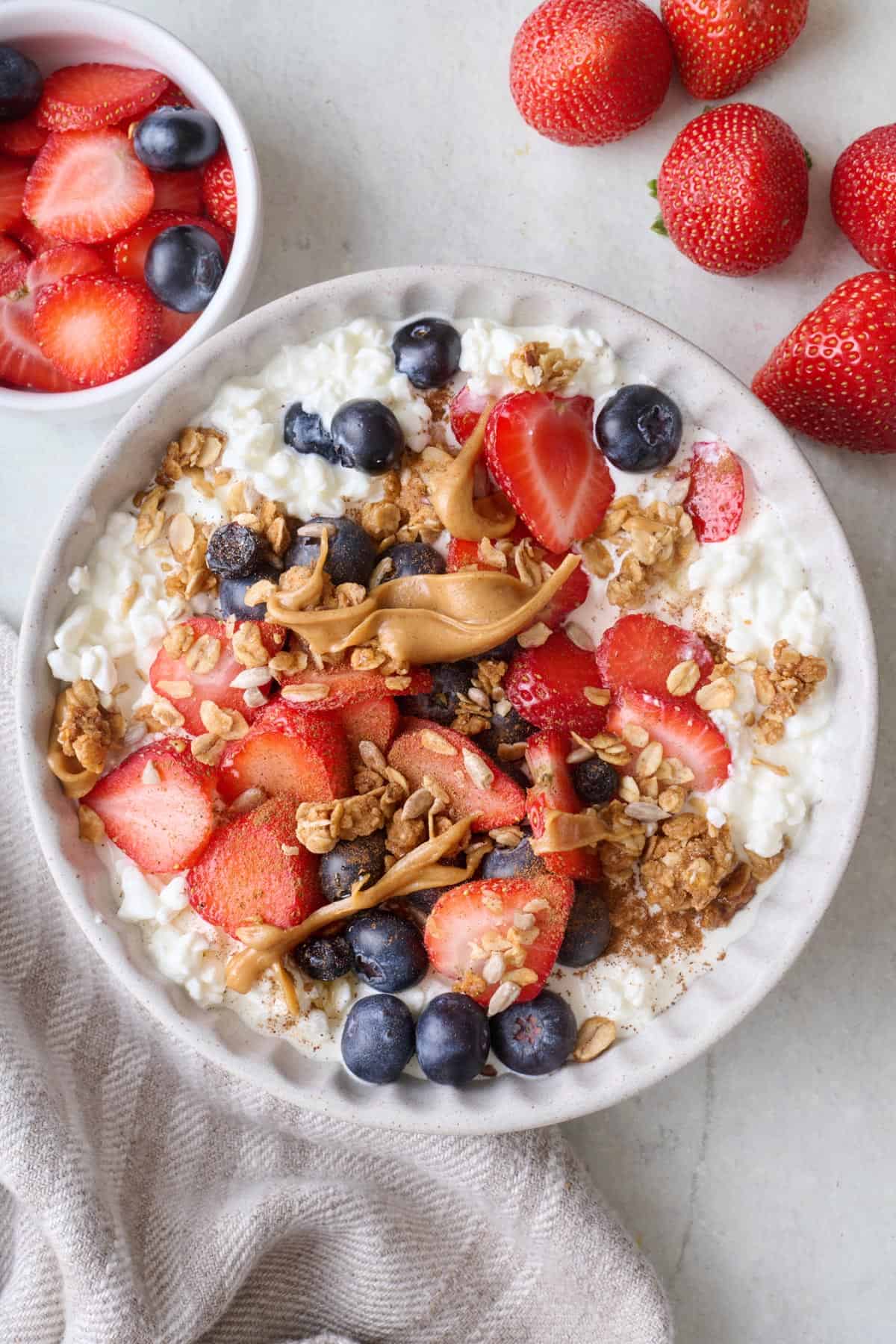 Sweet cottage cheese bowl with fresh fruit, honey, granola, and peanut butter.