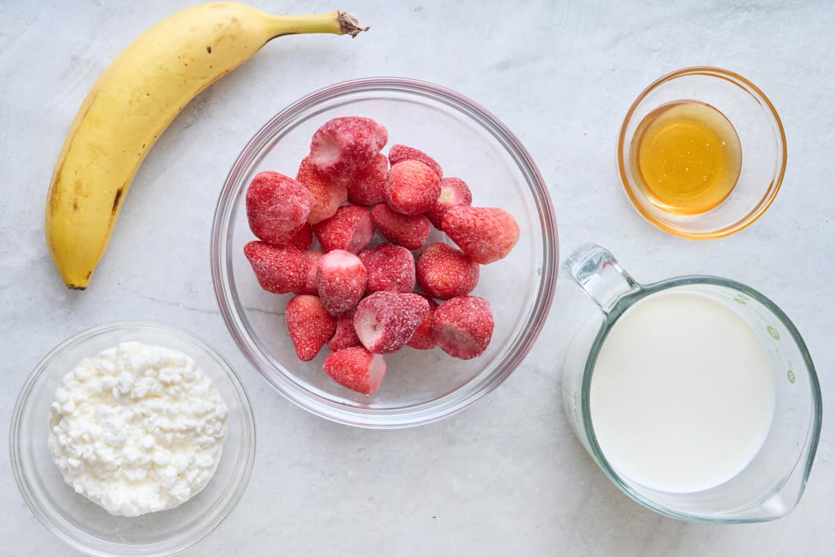 Ingredients for recipe: banana, cottage cheese, frozen strawberries, milk, and honey.