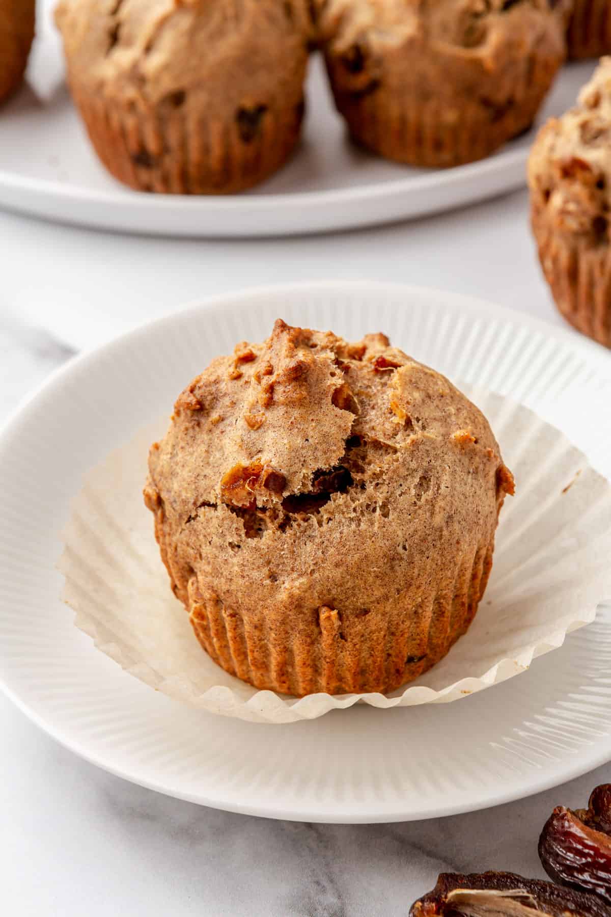 Date muffin on a small plate with parchment paper peeled back.