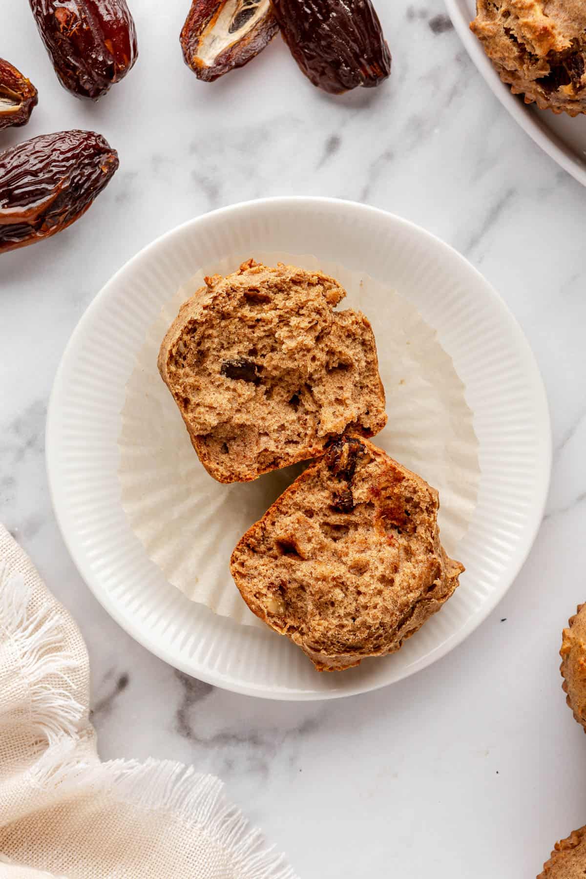 Date muffin split in half to show inside texture and chunks of dates throughout muffin.