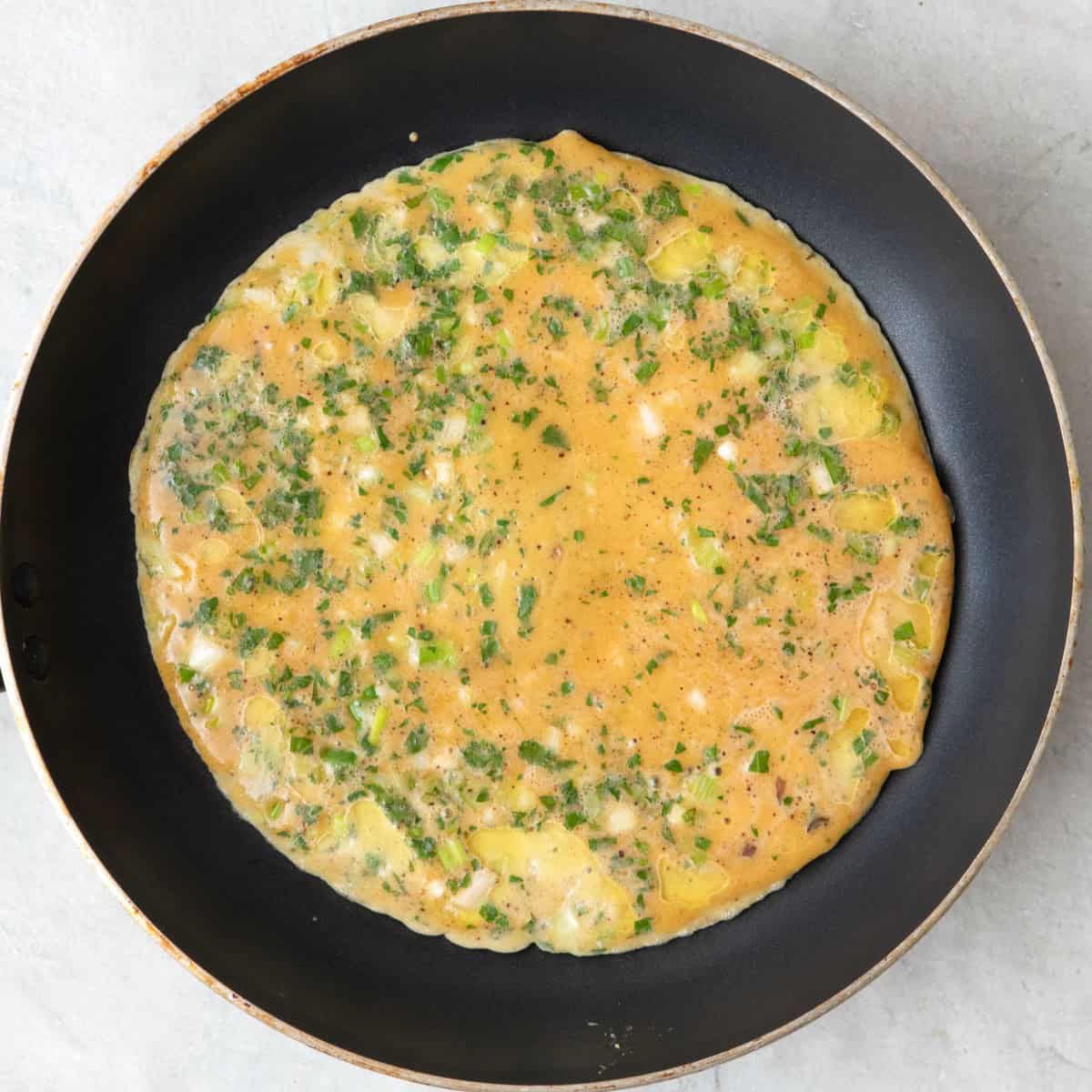 Enough egg mixture to fill the bottom of a skillet showing partially cooked recipe.