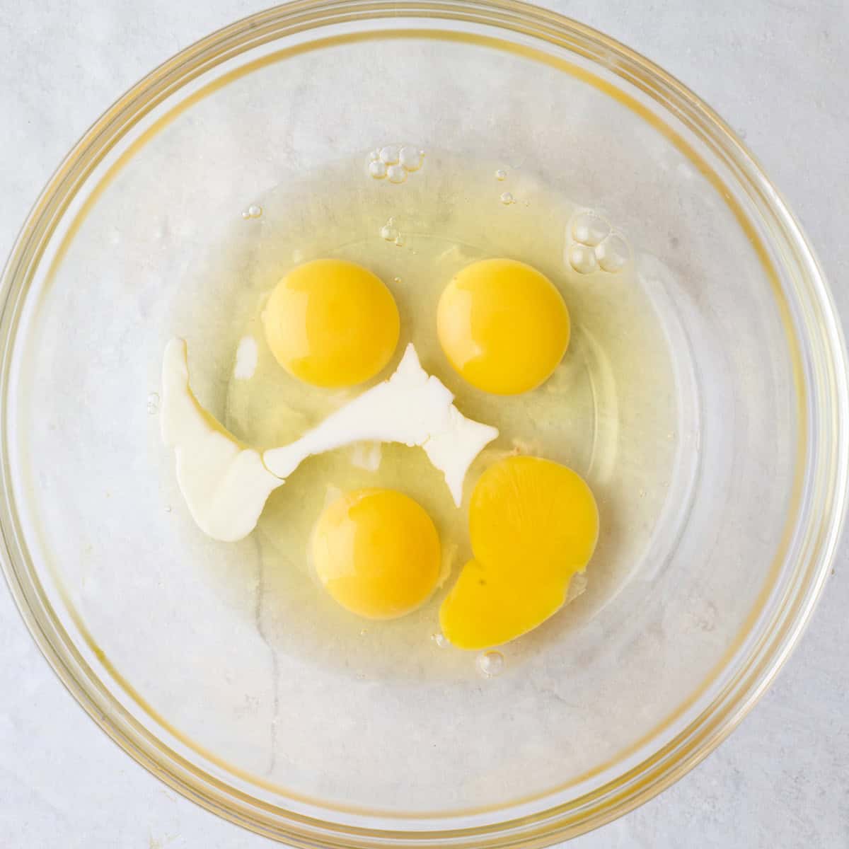 Cracked eggs and milk in a bowl.