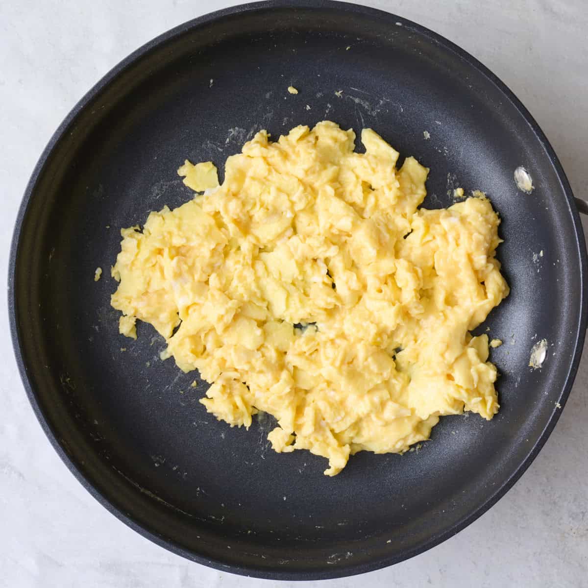 Fluffy scrambled eggs in a pan.