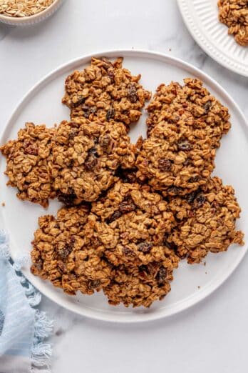 Cookies flat on a large round plate, with cookies overlapping each other, with a small plate with one cookie on it nearby.