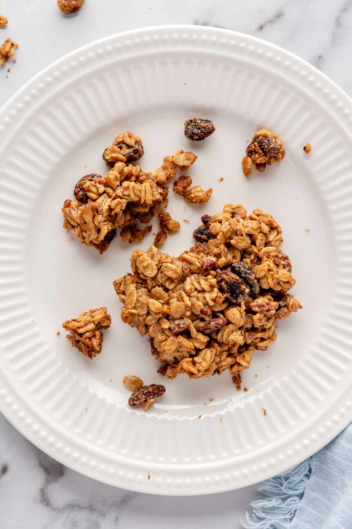 Close up on cookie on plate with a piece broken off and a few chunky crumbs on plate.