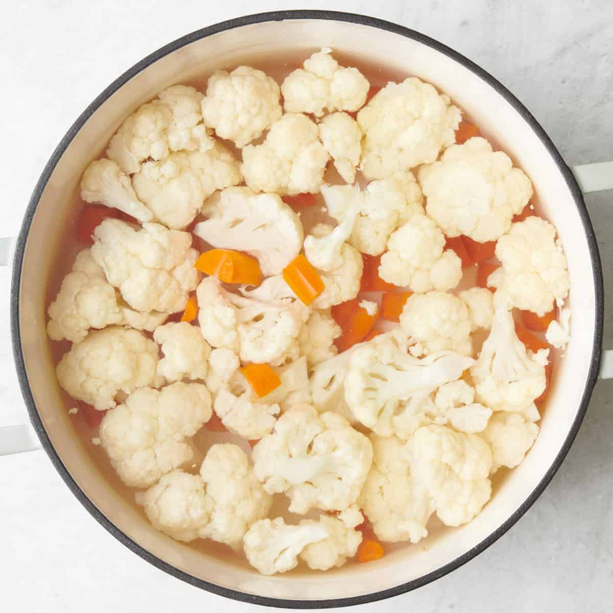 Carrots and cauliflower in a pot of boiled wate.