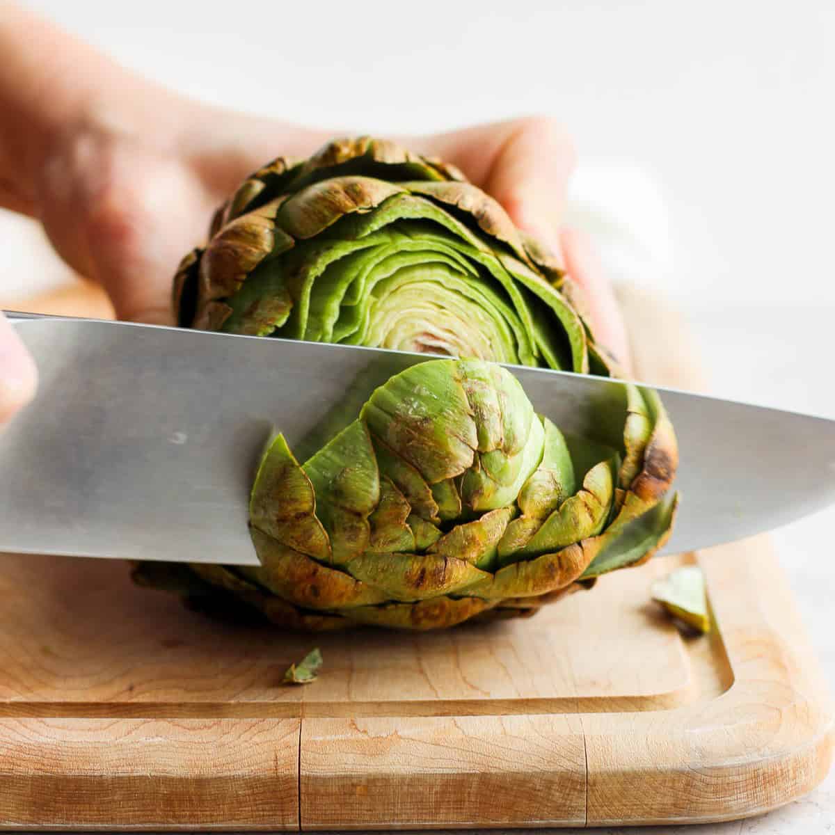 Cutting the top off of artichoke.