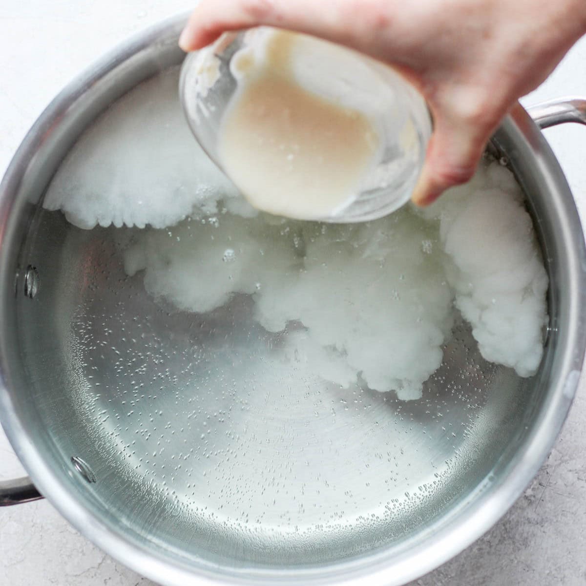 Pouring lemon and flour slurry into a pot of water.