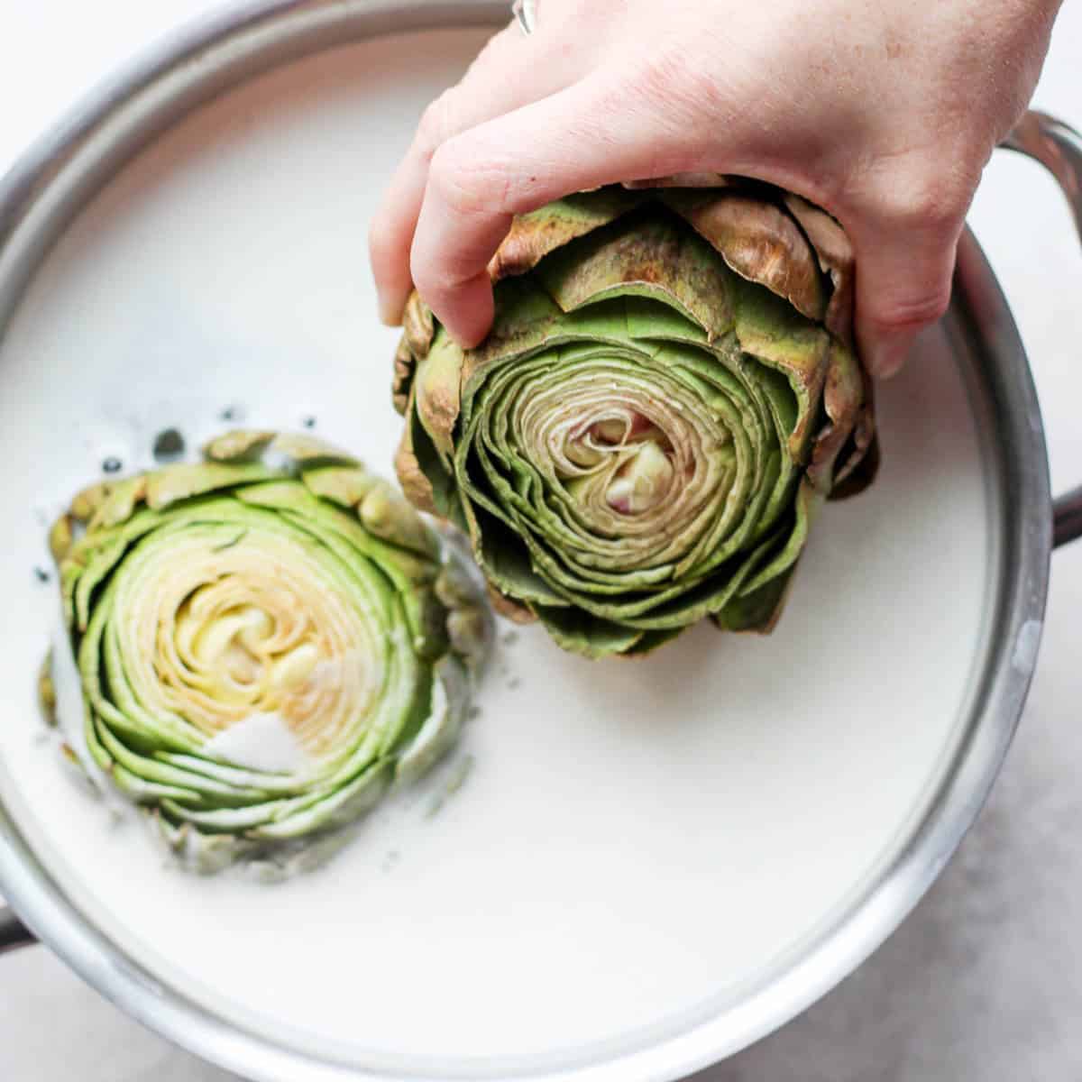 Adding prepped artichoke to pot.