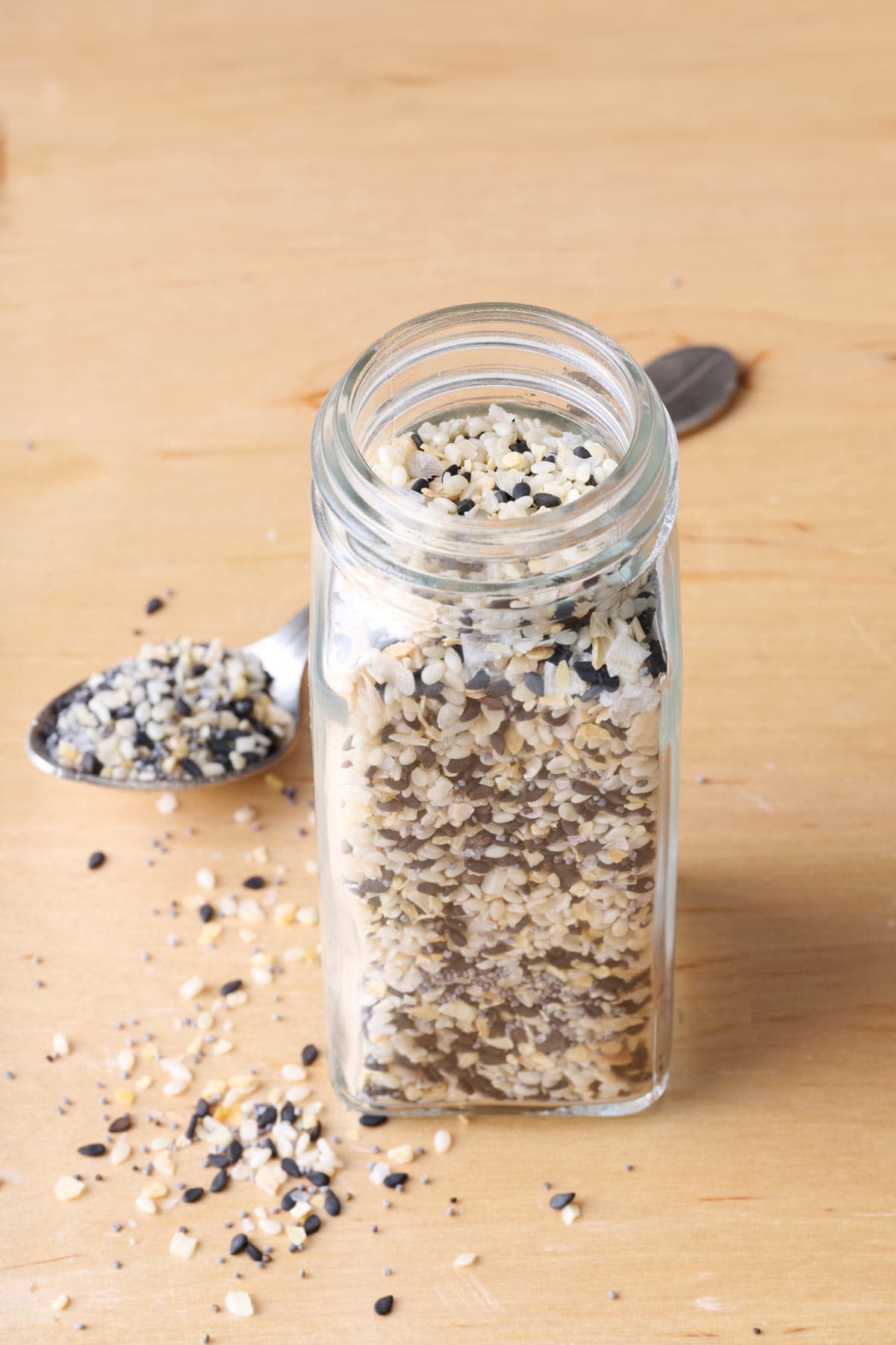 Everything bagel seasoning in a spice jar with some on a spoon nearby.