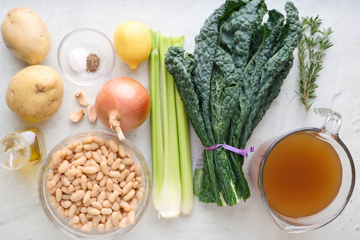 Ingredients for recipe: potatoes, salt and pepper, garlic, oil, beans, lemon, onion, celery, kale, rosemary, and broth.