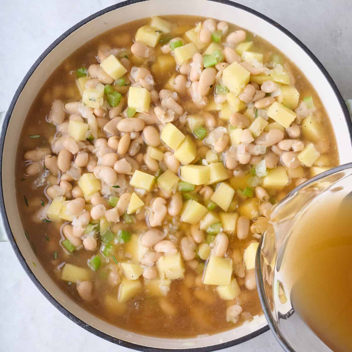 Adding broth to pot.