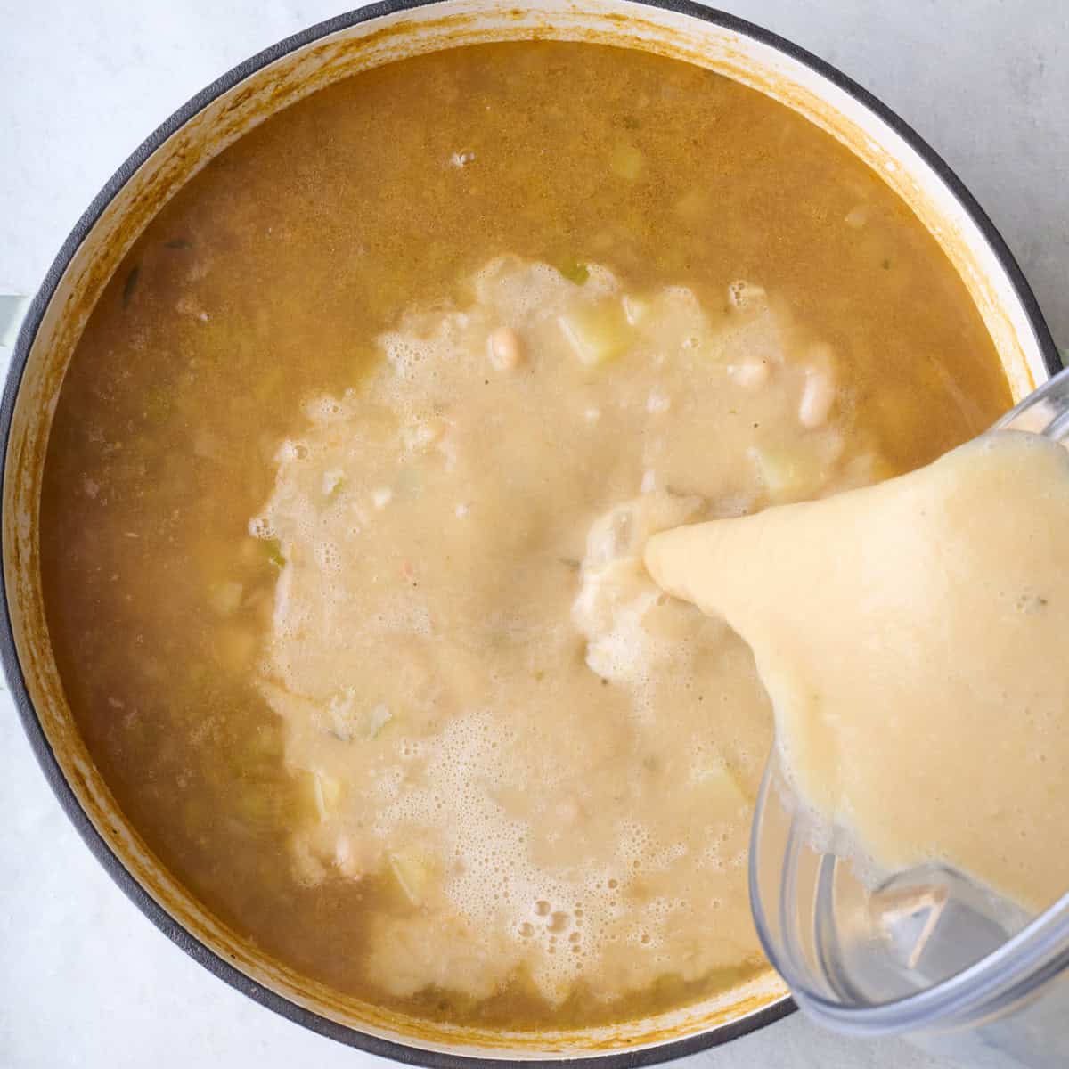 Pouring blended soup back into broth.