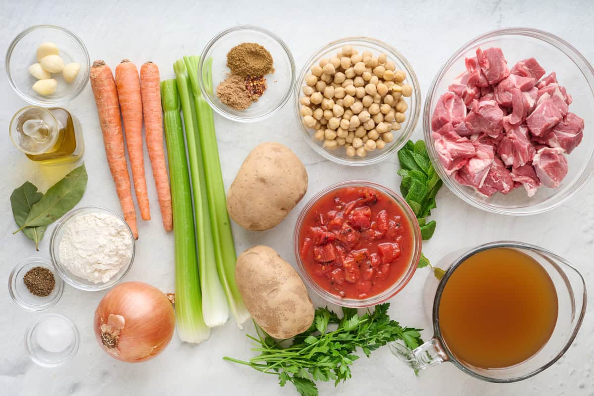 Ingredients for recipe: lamb, seasonings, garlic, oil, flour, carrots, celery, onion, potatoes, chickpeas, fresh herbs, and broth.