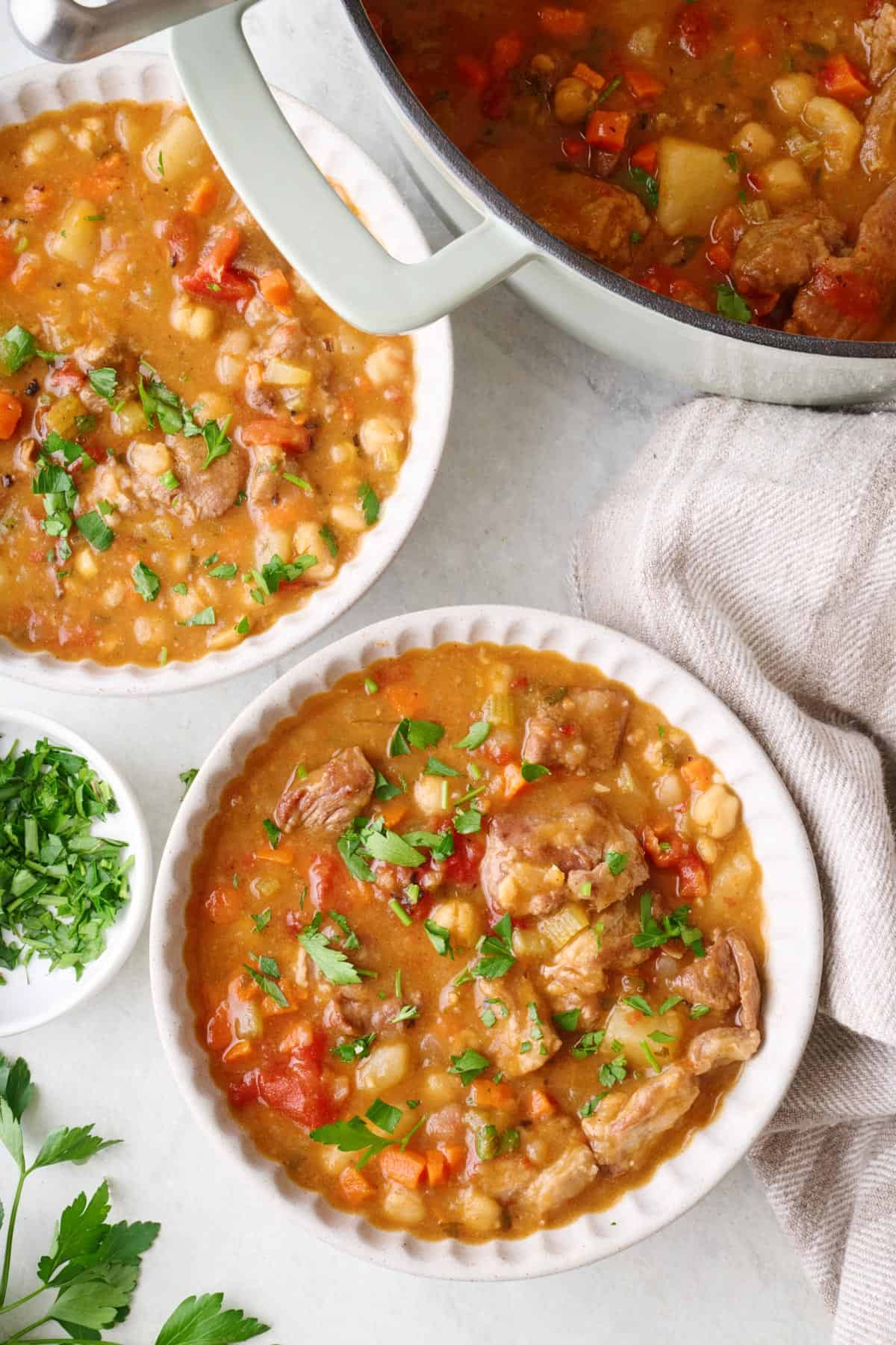 Hearty Lamb Stew in serving bowls with pot nearby.