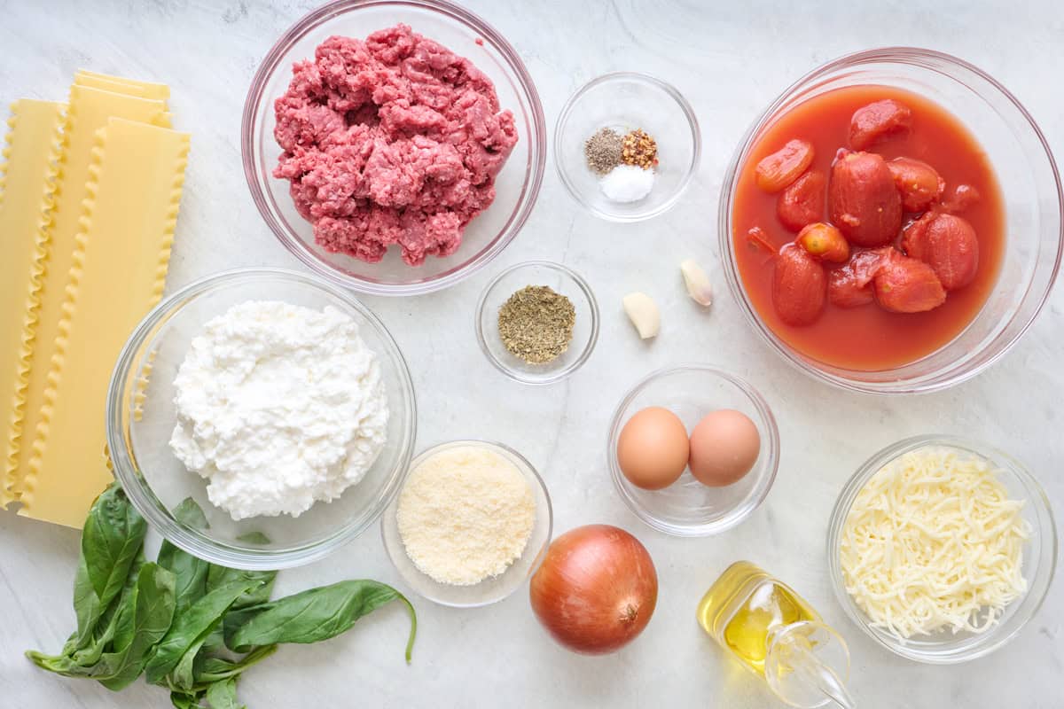 Ingredients for recipe: lasagna shets, fresh basil, cottage cheese, ground beef, parmesan, seasonings, garlic, eggs, onion, whole canned tomatoes, oil and shredded cheese.