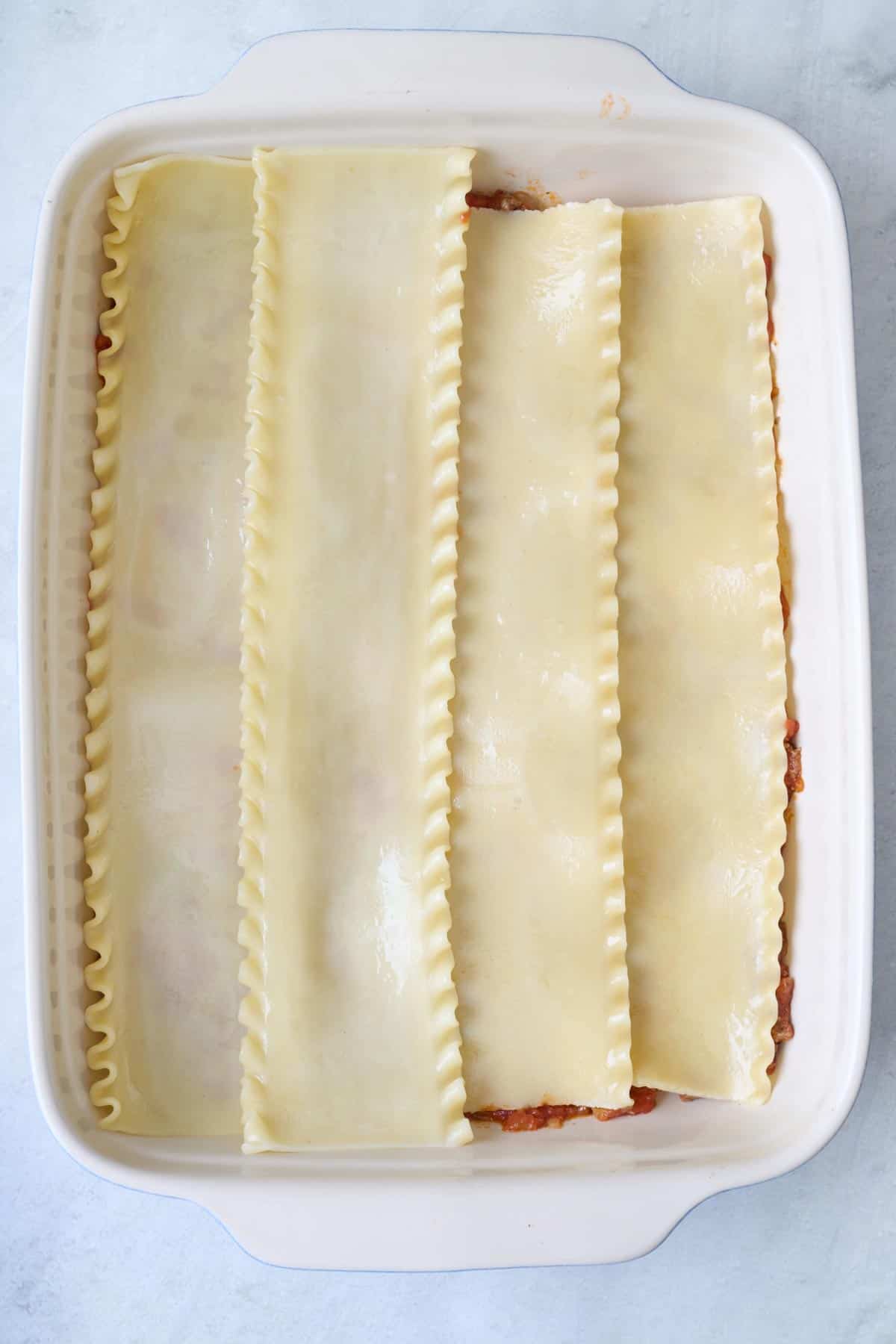 Par cooked lasagna sheets on top of meat sauce.