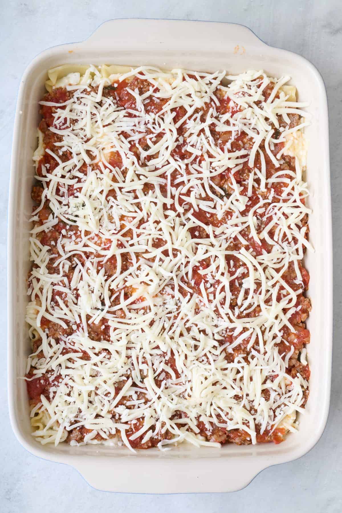 After another thin layer of tomato sauce and shredded cheese is added.