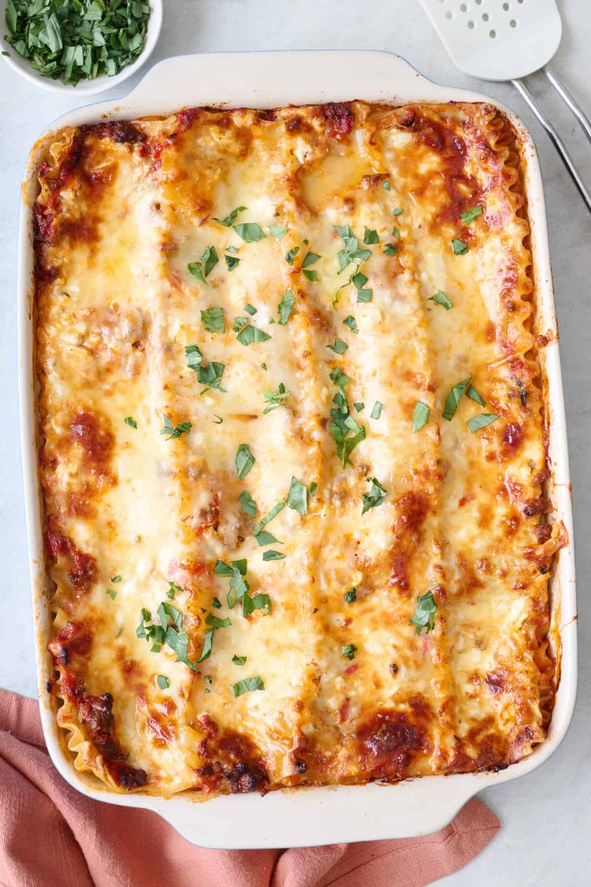 Cottage cheese lasagna in a baking dish garnished with fresh basil.