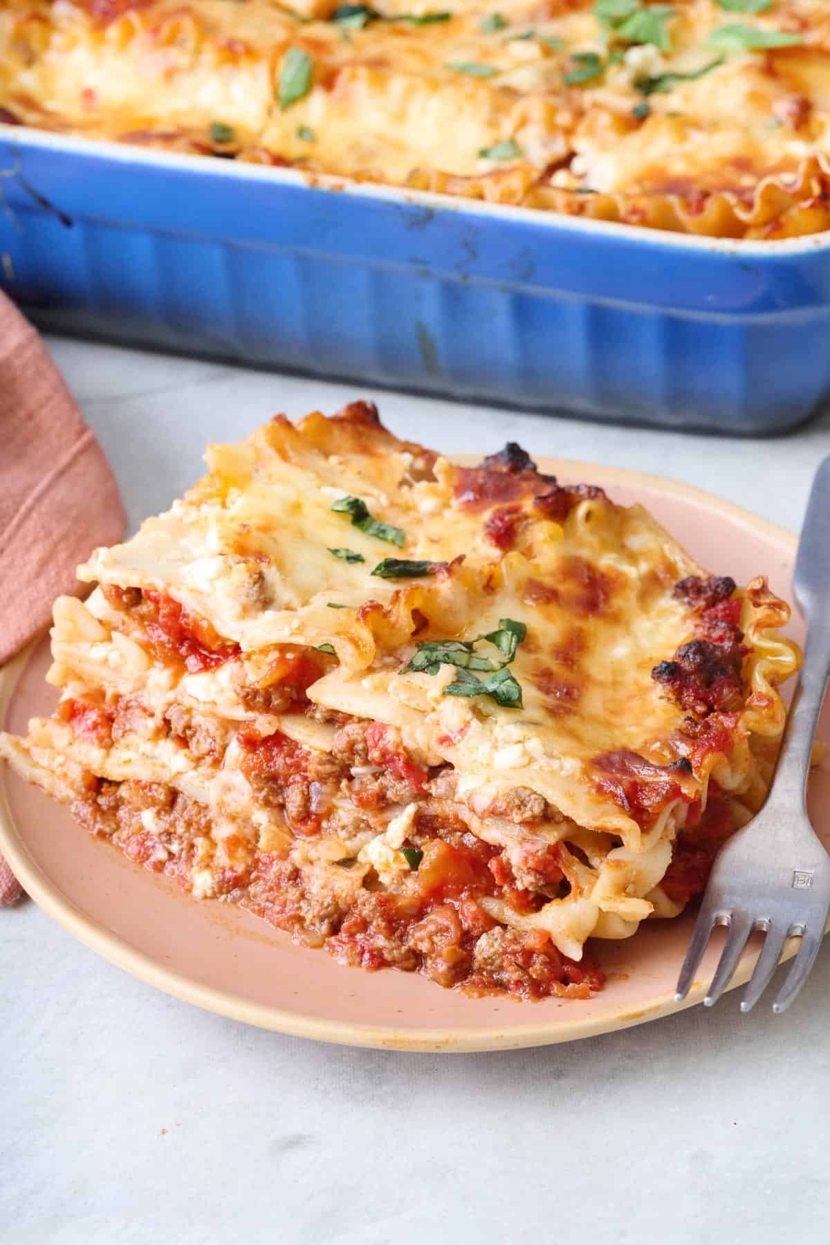 Large serving of cottage cheese lasagna on a plate with baking dish nearby.