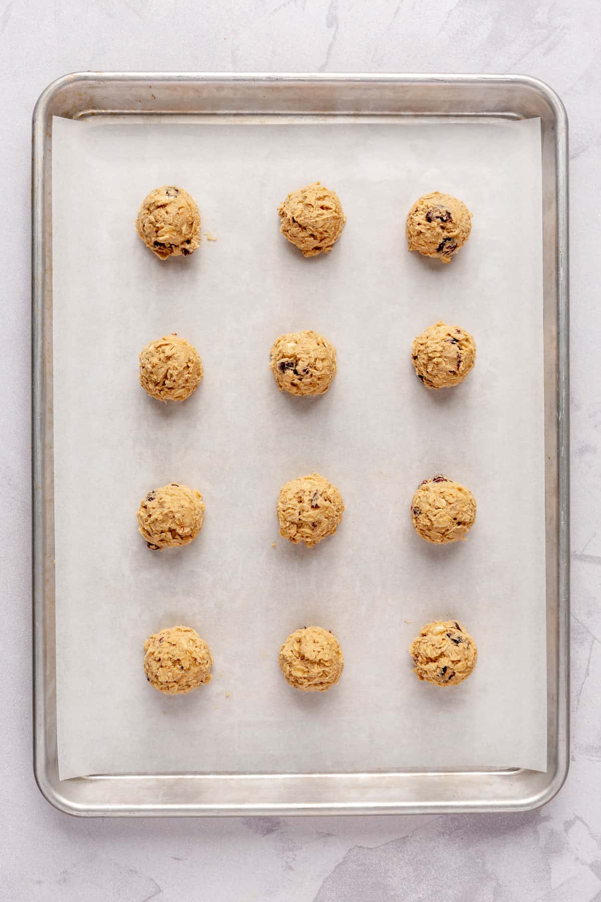 Cookie dough balls on a parchment lined baking sheet.