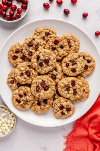 Oatmeal Cranberry Cookies on a plate with a small dish of white chocolate chips nearby.