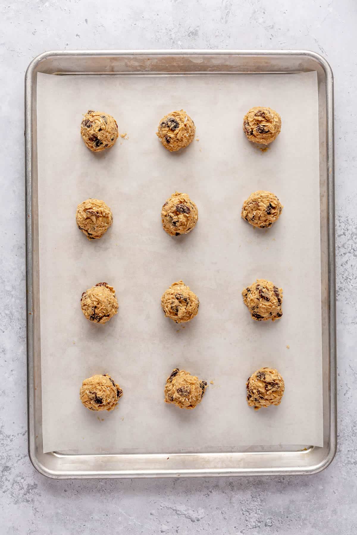 Cookie dough balls on a lined baking sheet.