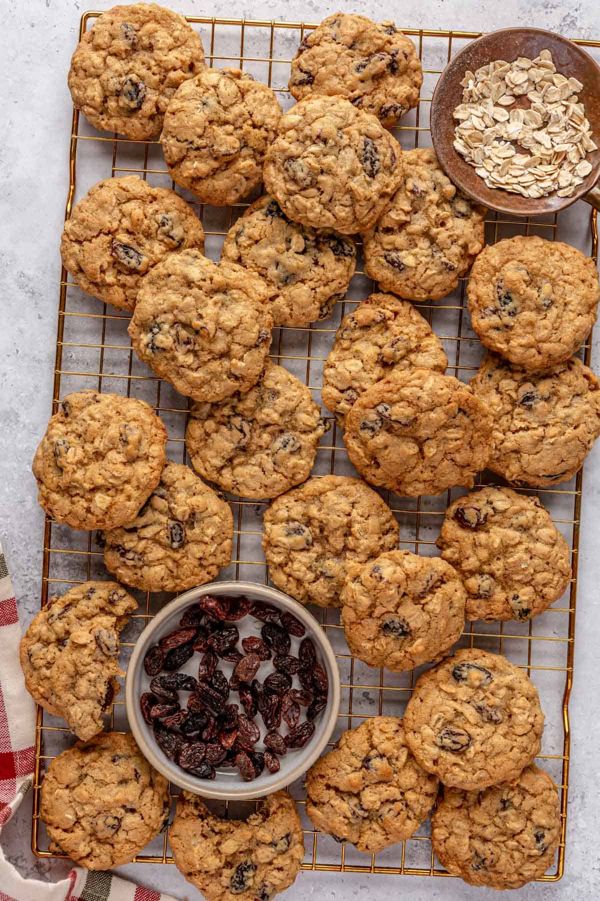 Cookies on a wire rack, small dish of raisins and oats nearby.