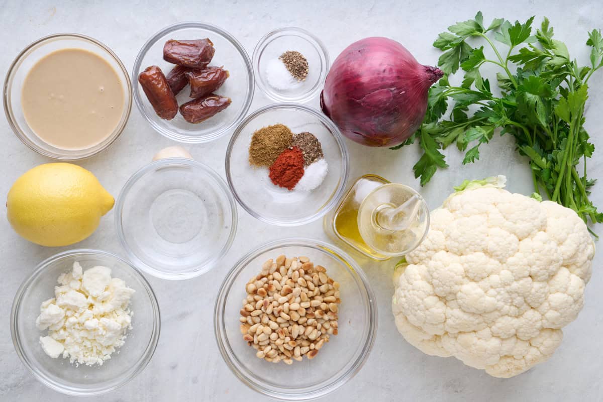 Ingredients for recipe: tahini, lemon, feta, dates, spices, toasted pine nuts, red onion, oil, parsley, and cauliflower.