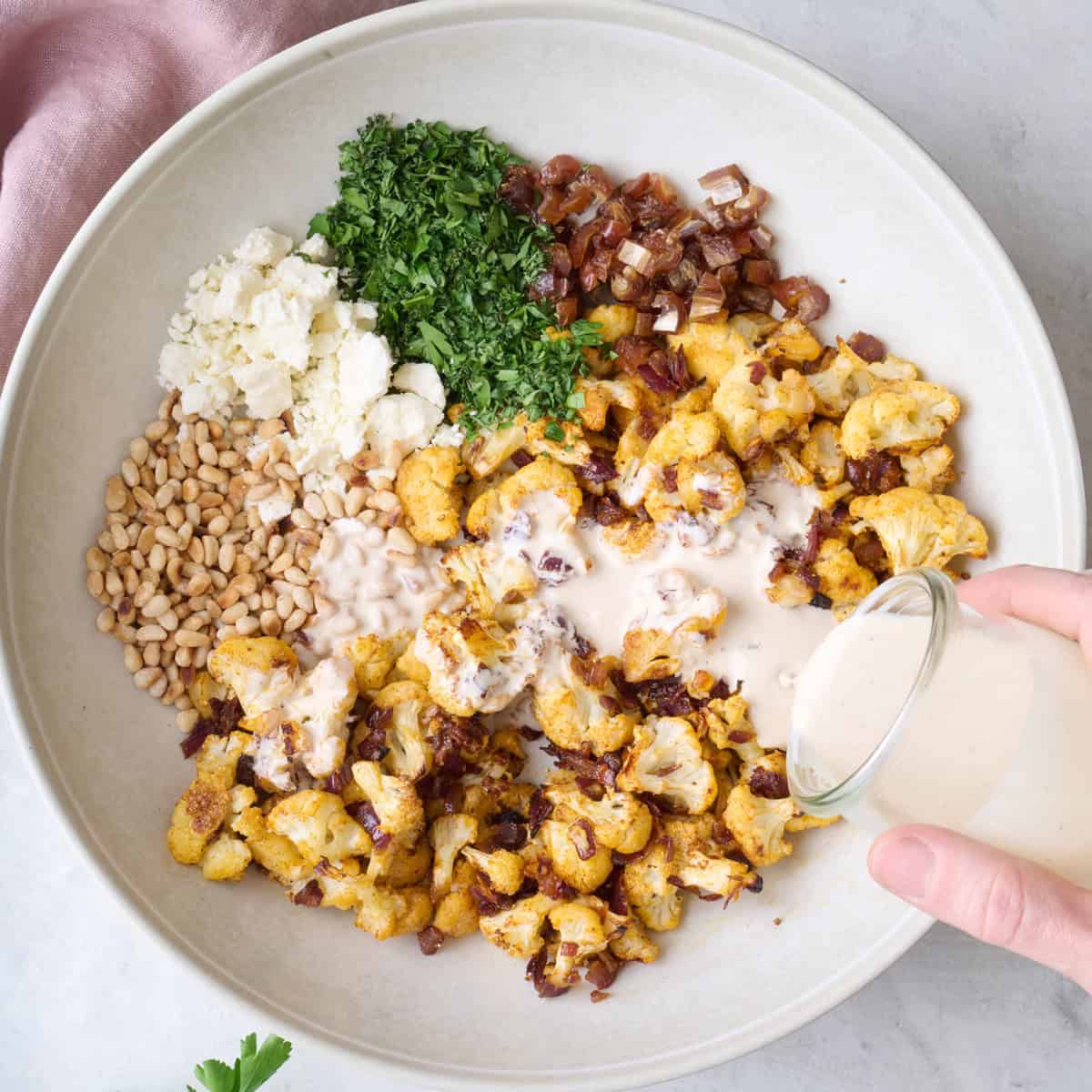 Pouring dressing over salad in a bowl.