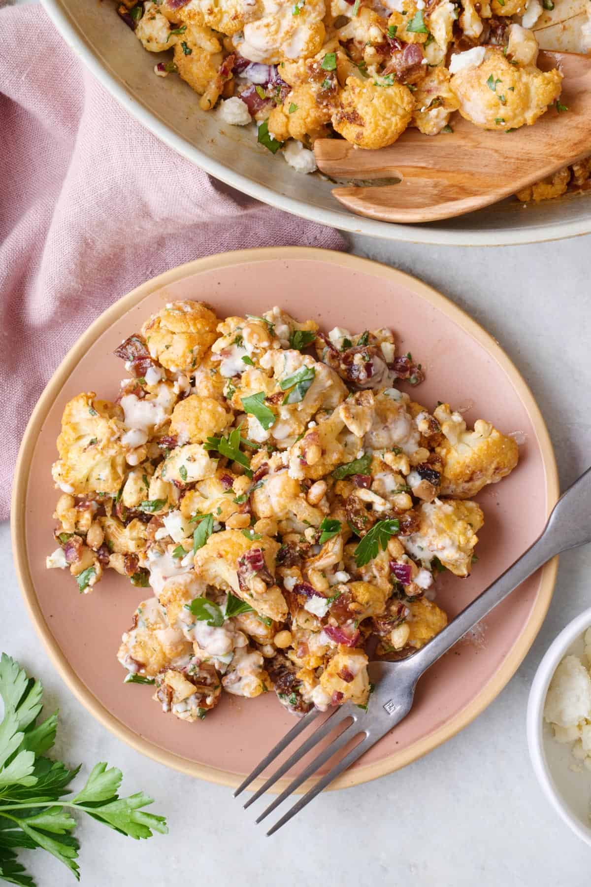 Roasted cauliflower salad on a platter garnished with serving set resting on platter nearby.